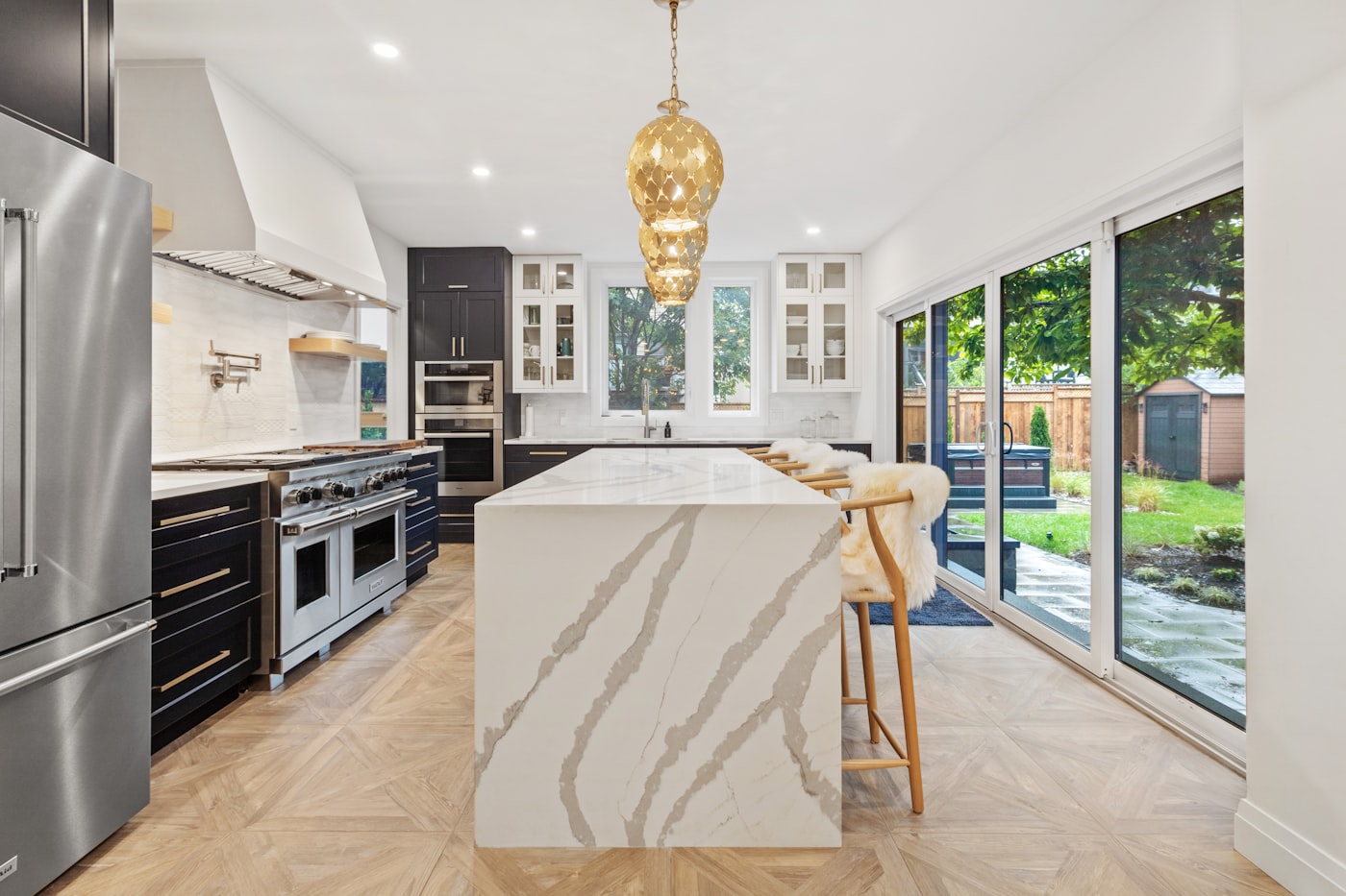 Bright remodeled kitchen with marble waterfall island and navy cabinetry